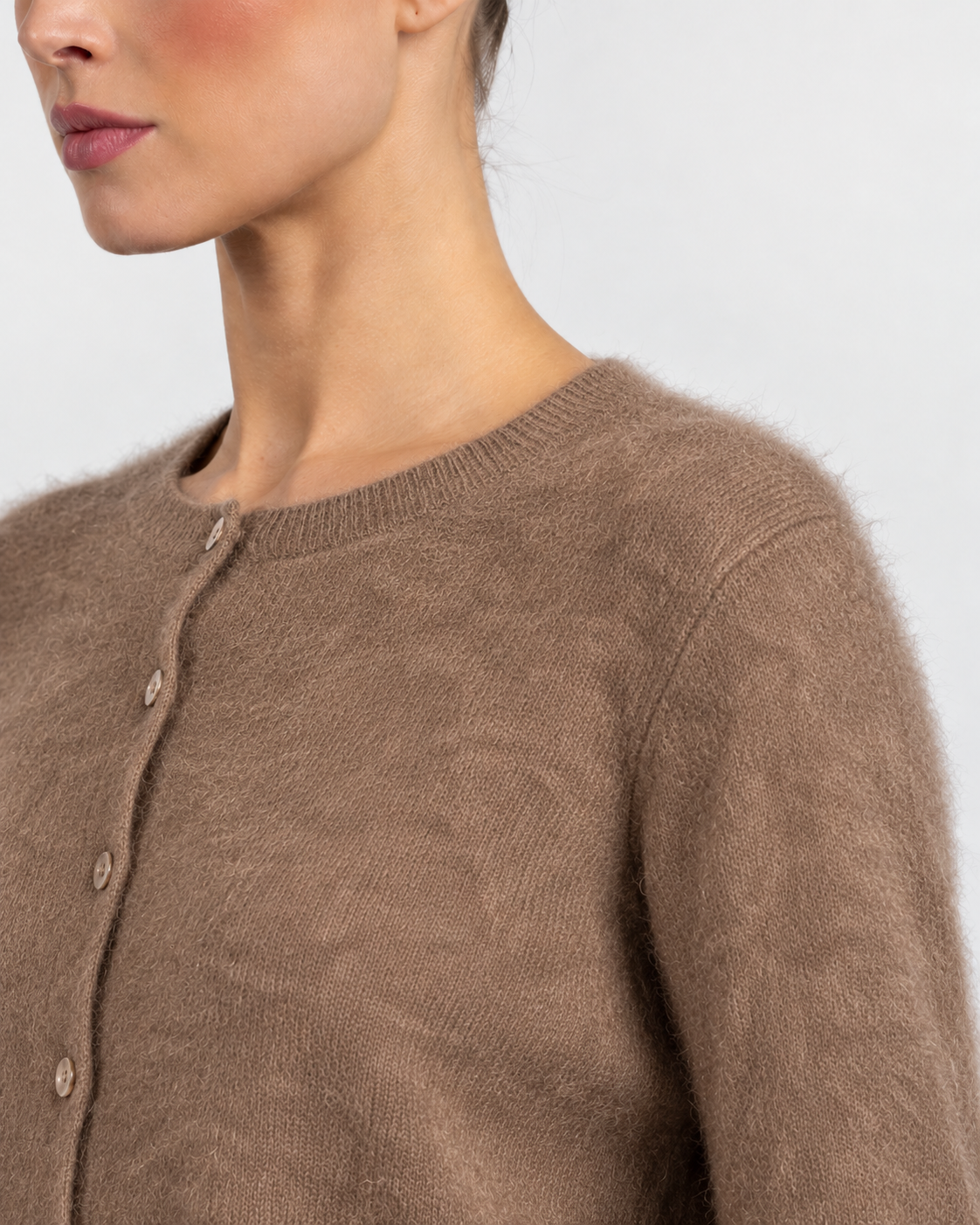 Close-up of a model wearing a fuzzy taupe-brown knit cardigan sweater with a buttoned front.