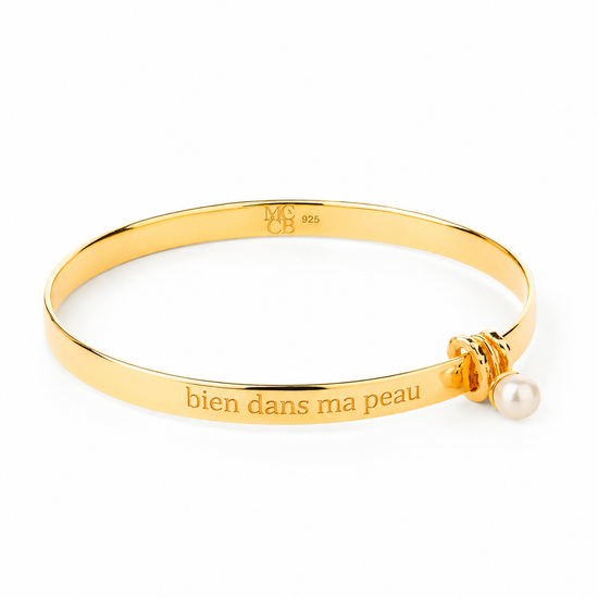 Gold bracelet with a pearl charm and engraved text on a white background