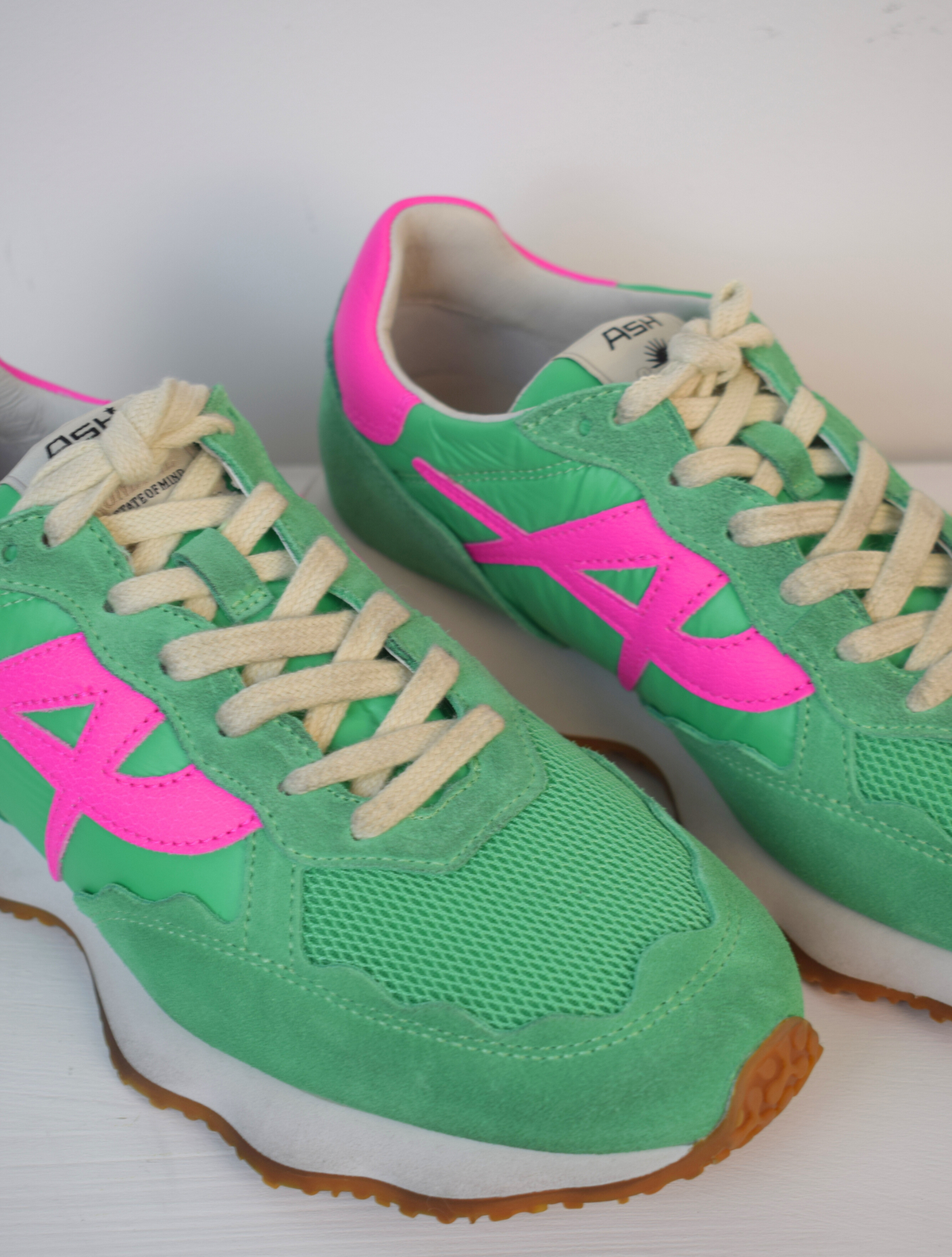 Green trainer with pink A on side and pink patch on back of heel 