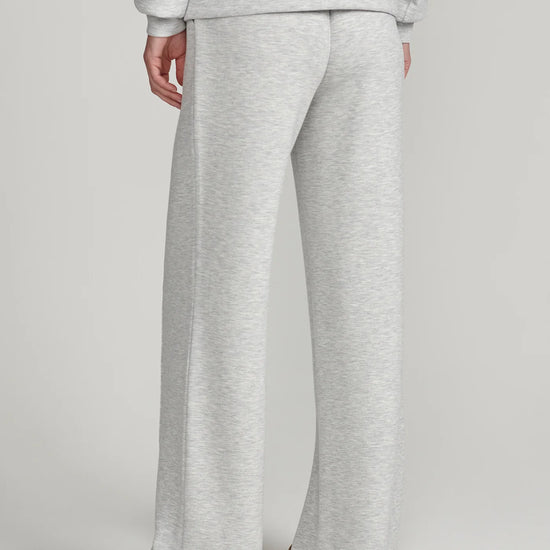 A person shown from the back wearing light heather gray wide-leg sweatpants and a matching sweatshirt, photographed against a plain light gray studio background.