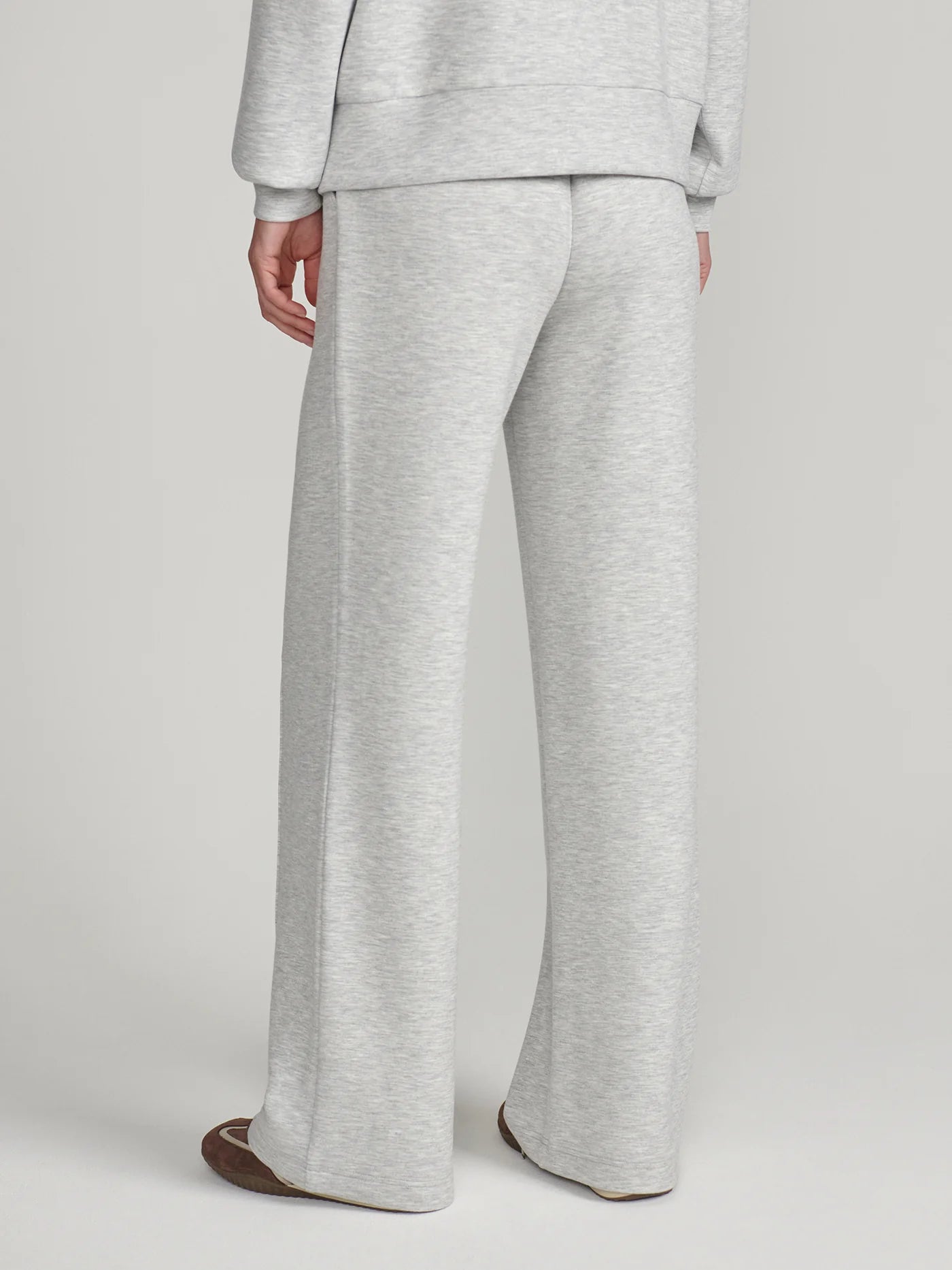 A person shown from the back wearing light heather gray wide-leg sweatpants and a matching sweatshirt, photographed against a plain light gray studio background.