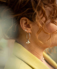 Large silver hoop earrings with flying bee pendants and a rice pearl drop with butterfly earring fastenings