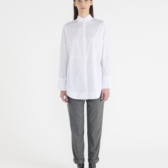 White long classic shirt with wide cuffs and panelling detailing on the front. Front view.