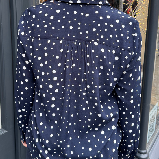 Navy long sleeved shirt with different sized white dots, styled with dark denim