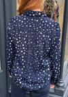 Navy long sleeved shirt with different sized white dots, styled with dark denim