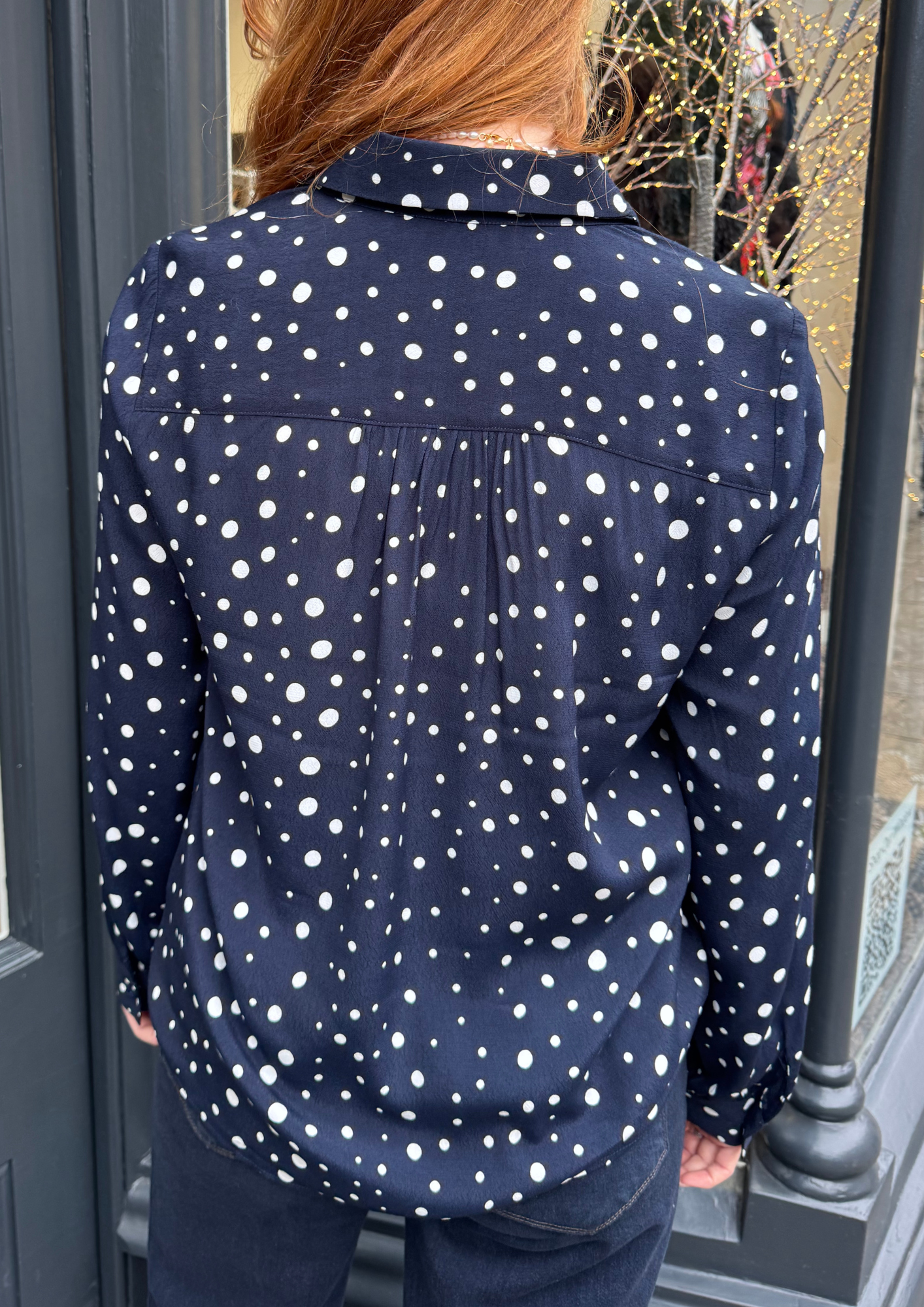 Navy long sleeved shirt with different sized white dots, styled with dark denim