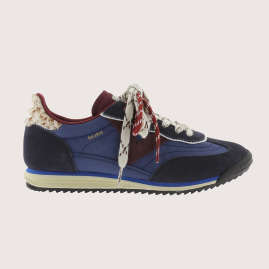 A low-top fashion sneaker, featuring navy blue suede and mesh panels, burgundy accents, patterned white and burgundy laces, and a cream midsole, shown against a plain light gray background.