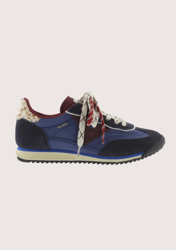 A low-top fashion sneaker, featuring navy blue suede and mesh panels, burgundy accents, patterned white and burgundy laces, and a cream midsole, shown against a plain light gray background.