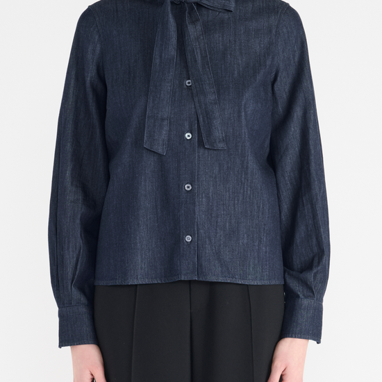 Dark denim classic shirt shape with tie at the neck. Close up view. 