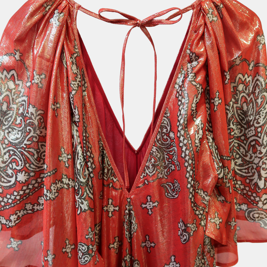 Red and gold patterned dress on a hanger against a white background