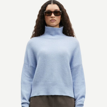 Women wearing a soft baby blue jumper and brown sunglasses.