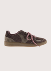 A low-top sneaker in dark brown suede and gray fabric panels, featuring dusty pink laces and a tan rubber sole, shown against a light beige background.