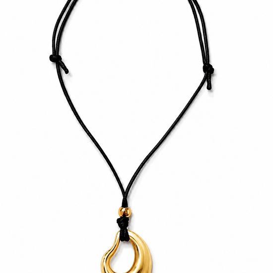 Gold pendant on a black cord against a white background