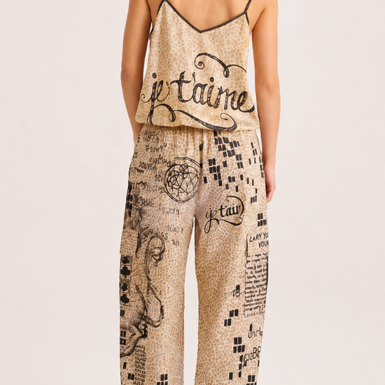 A woman shown from the back wearing a beige and black graphic print camisole top and matching wide-leg pants with black high heels, against a plain light background.