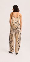 A woman shown from the back wearing a beige and black graphic print camisole top and matching wide-leg pants with black high heels, against a plain light background.