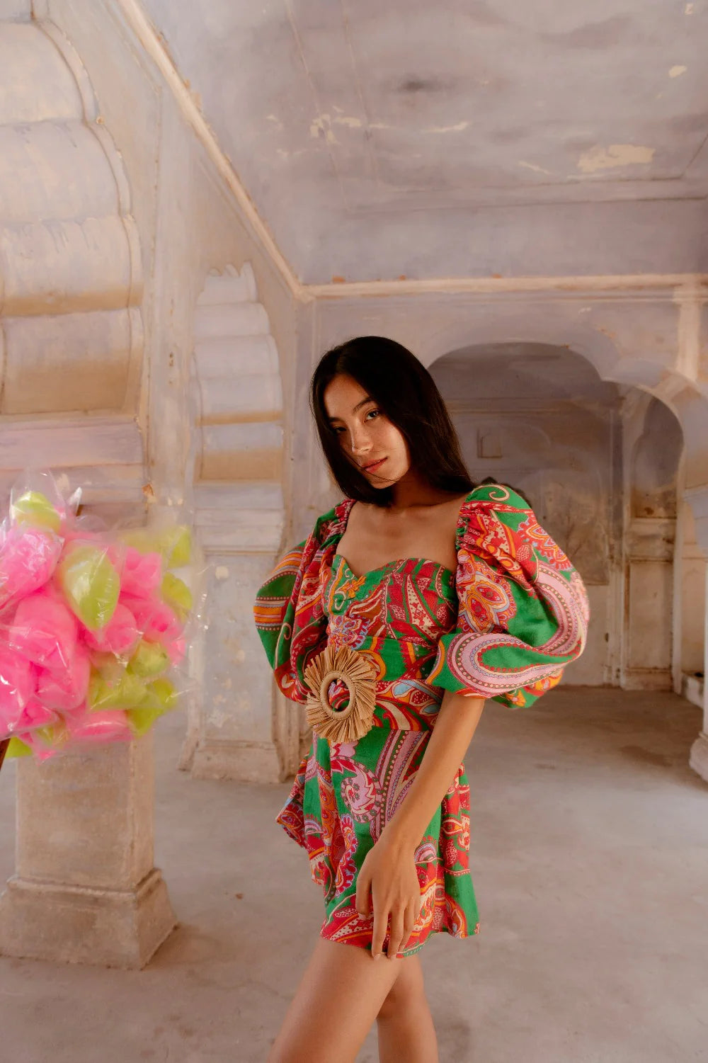 Green red and pink paisley print playsuit with oversized puff sleeves and a circle raffia belt