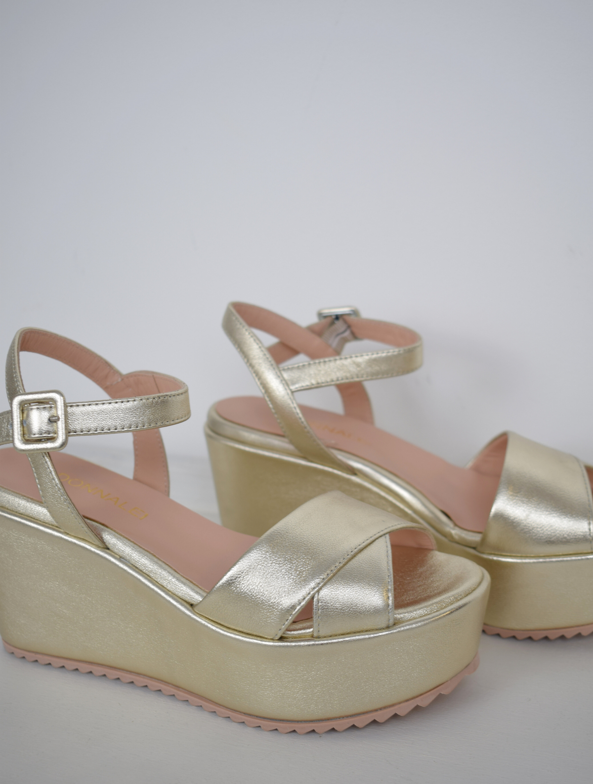 A flat gold sandal with large platform and ankle strap 