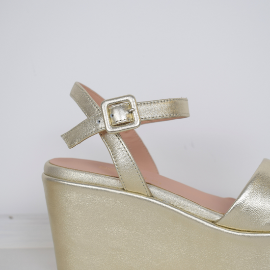 A flat gold sandal with large platform and ankle strap 