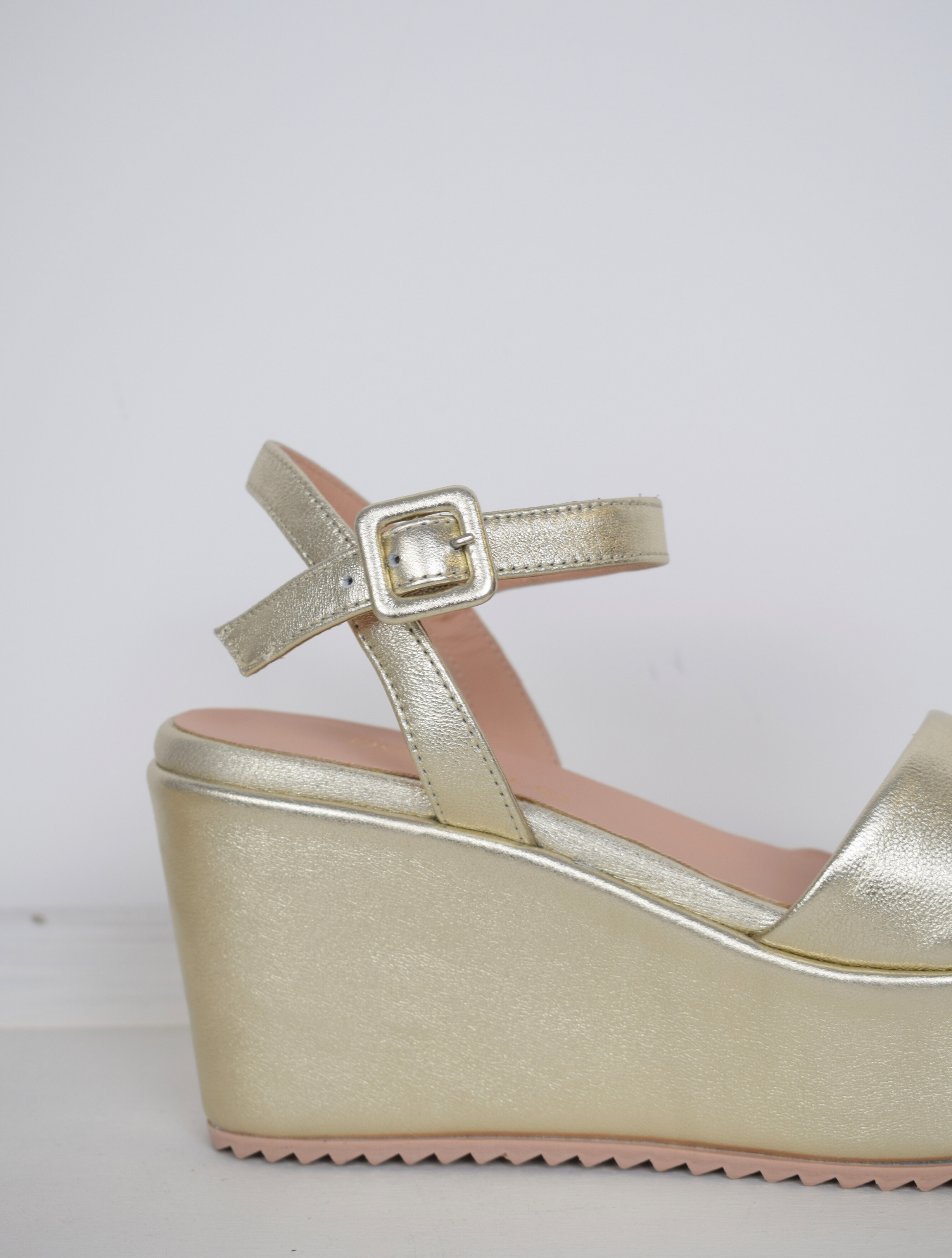 A flat gold sandal with large platform and ankle strap 