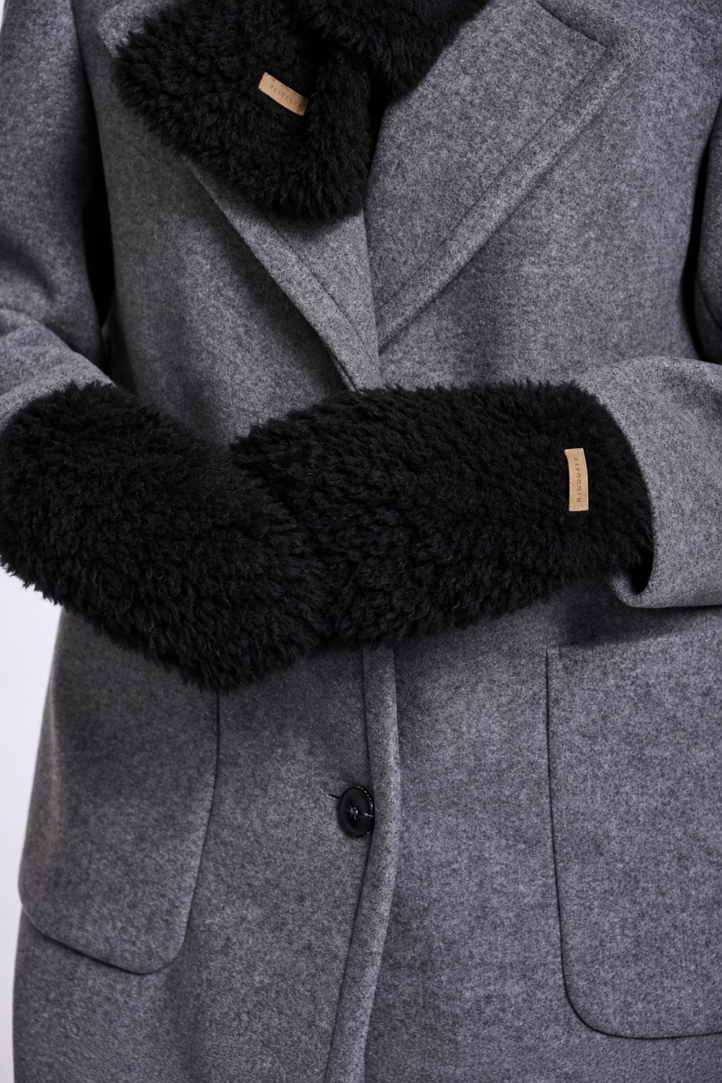 Close-up of a gray wool coat with black faux-fur trim on the collar and cuffs, featuring a small tan brand tab.