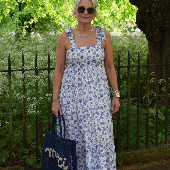 Strappy summer dress with ecru background and blue sea shelll and crab print with tiered skirt