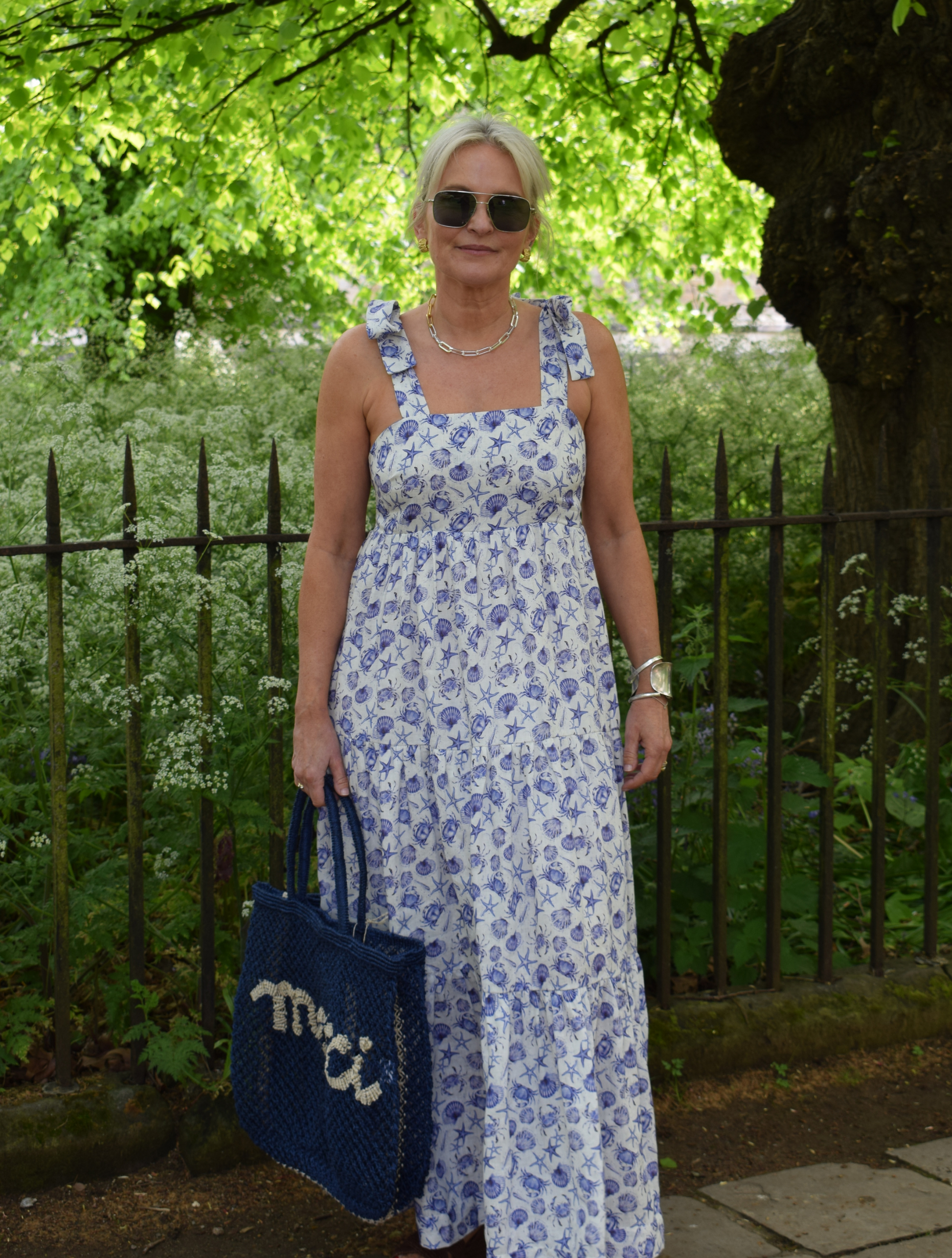 Strappy summer dress with ecru background and blue sea shelll and crab print with tiered skirt