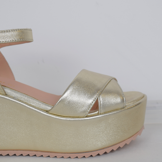 A flat gold sandal with large platform and ankle strap 