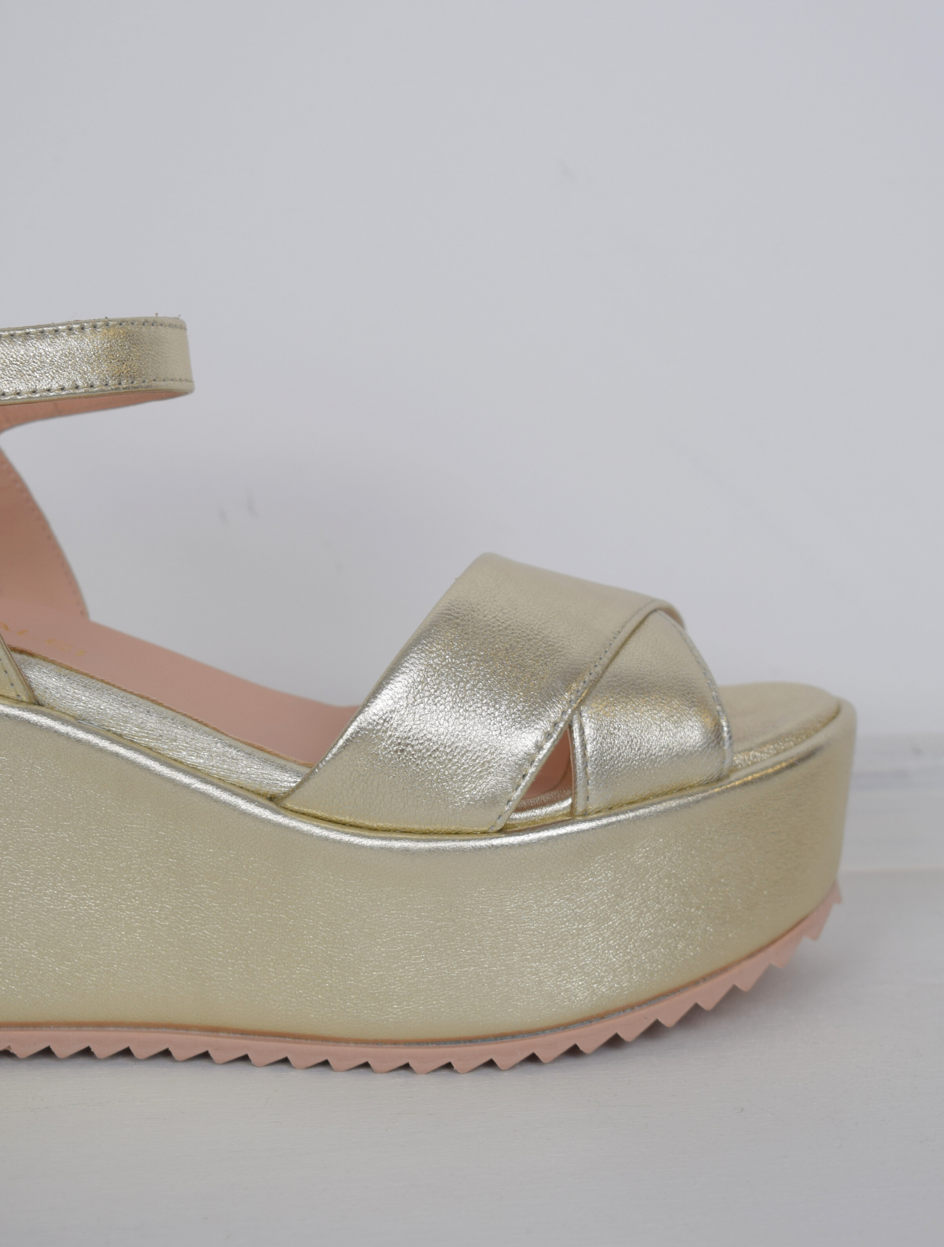 A flat gold sandal with large platform and ankle strap 