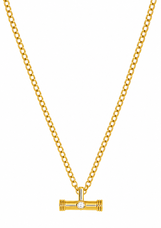 A gold chain necklace with a horizontal bar pendant featuring a small clear gemstone in the center, displayed against a solid white background.