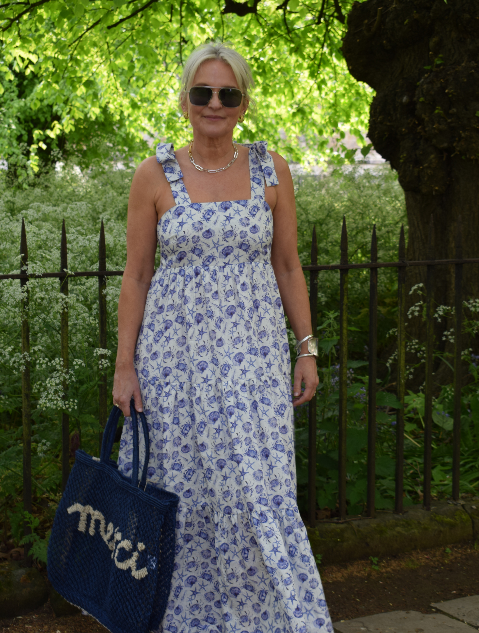 Strappy summer dress with ecru background and blue sea shelll and crab print with tiered skirt