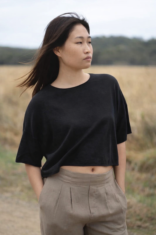 Woman wearing a black top and beige pants standing in a field