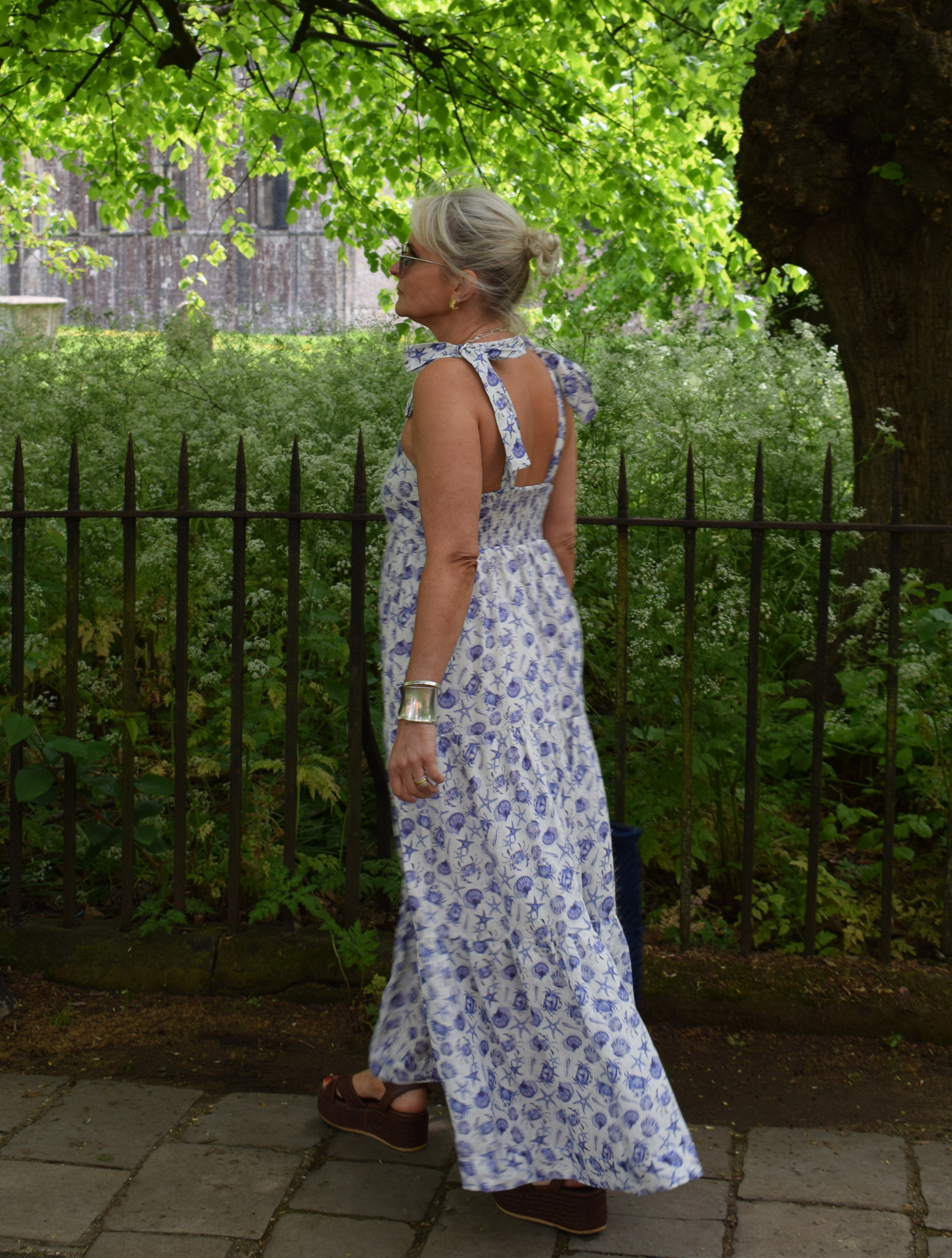 Strappy summer dress with ecru background and blue sea shelll and crab print with tiered skirt