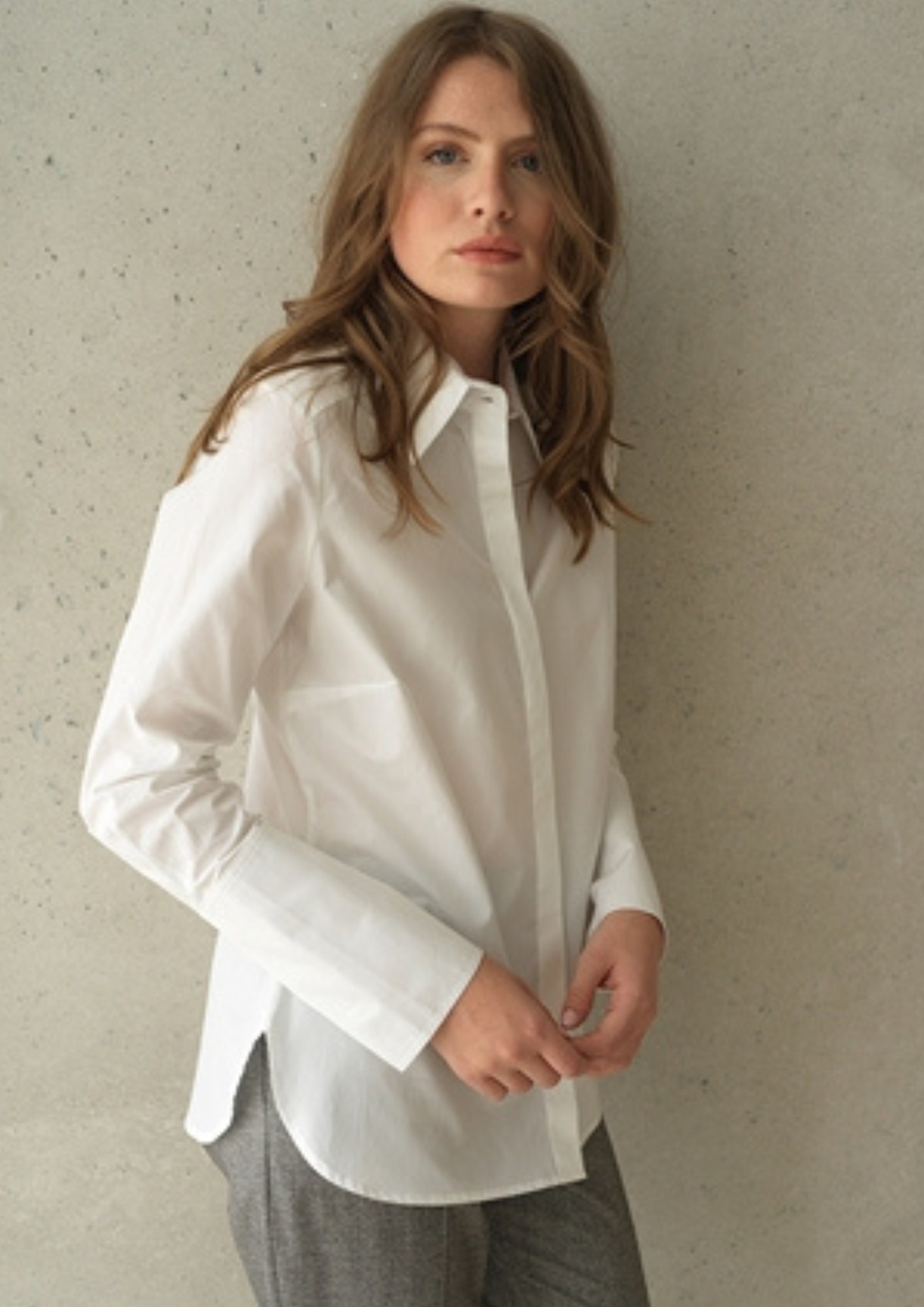 White button up shirt with a curved hem and wide collar, with three buttons  at the neck. 