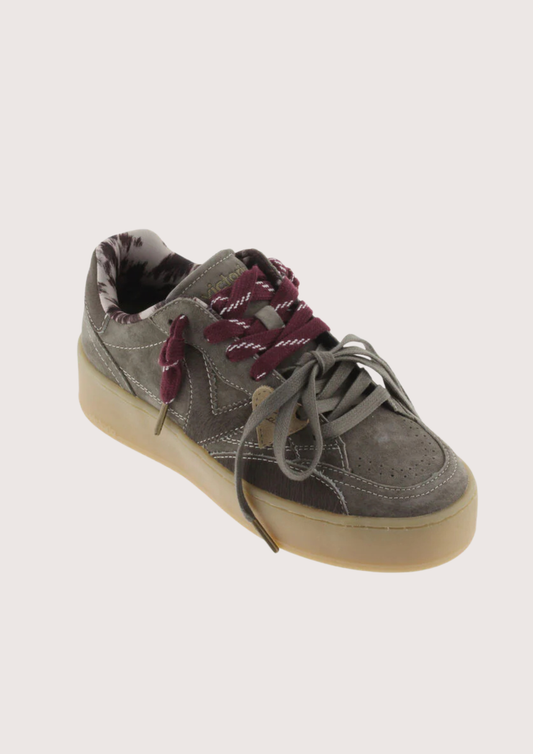 A low-top platform sneaker in dark gray suede and leather, featuring a thick beige gum sole, gray laces, and burgundy ribbon laces tied in a bow.