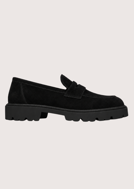 Black suede loafer with a black sole on a grey background