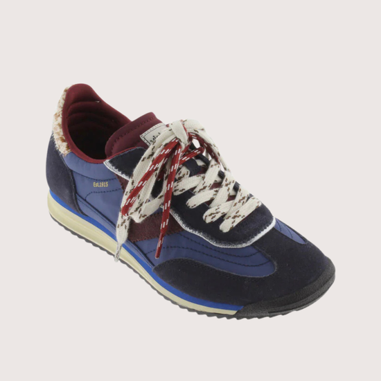 A low-top fashion sneaker, featuring navy blue suede and mesh panels, burgundy accents, patterned white and burgundy laces, and a cream midsole, shown against a plain light gray background.