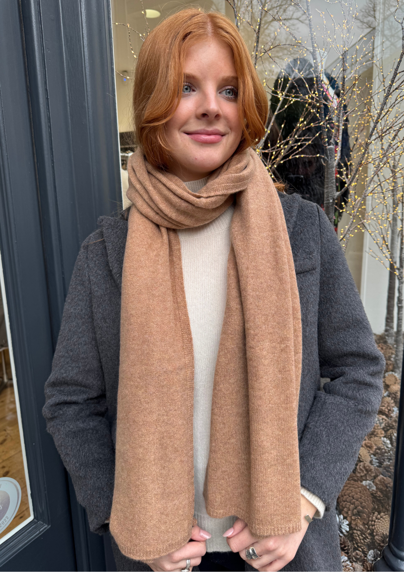 Model wearing grey coat and camel cashmere scarf.