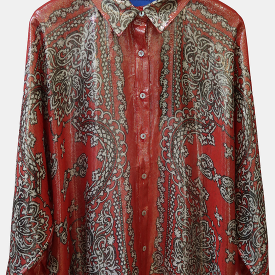 Red and gold patterned shirt on a hanger against a white background.