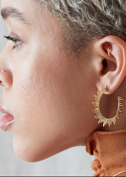 large gold hoop earrings with varying sized spike detailing along the edging with butterfly fastening from rachel jackson model shot