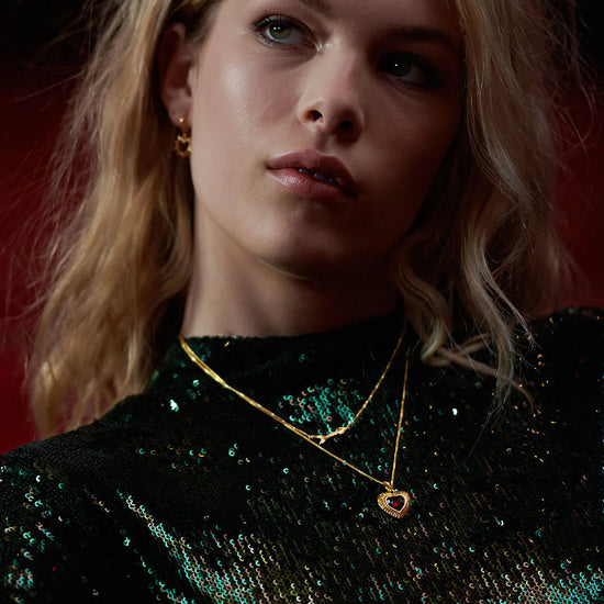 gold heart with red stone inside on a gold chain from rachel jackson model shot