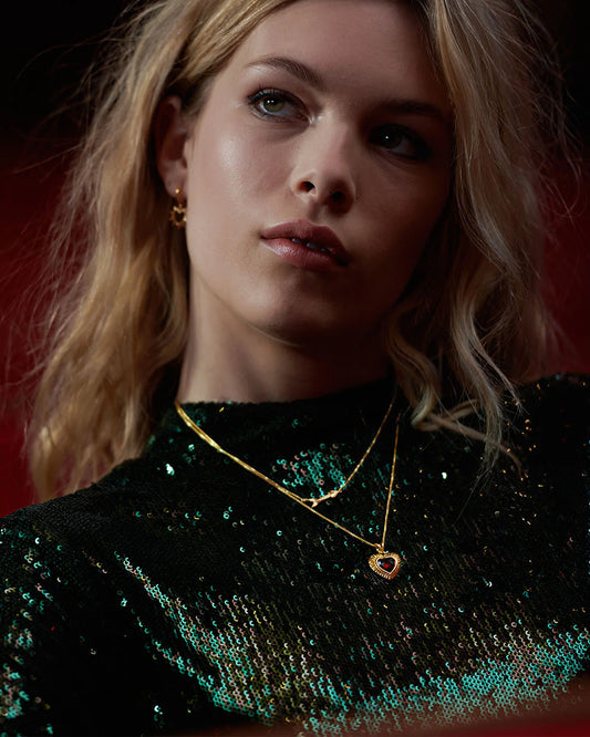 gold heart with red stone inside on a gold chain from rachel jackson model shot