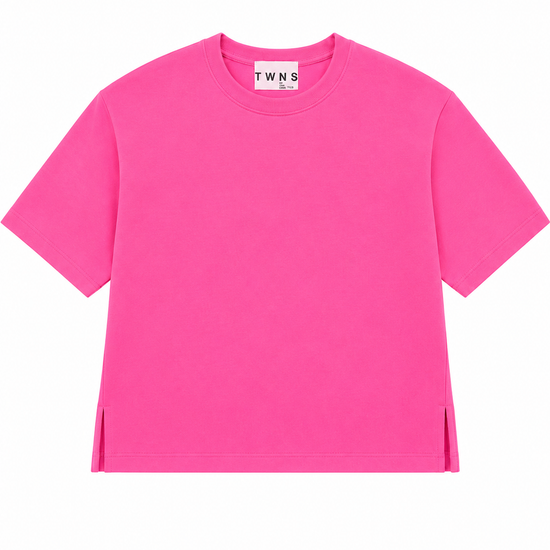 A bright pink short-sleeve crewneck t-shirt with side slits at the hem, displayed flat against a solid white background. The inner neck label shows the brand name 'TWN S'.