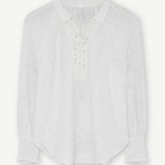 Flat lay of the white blouse with lace insert at the neck