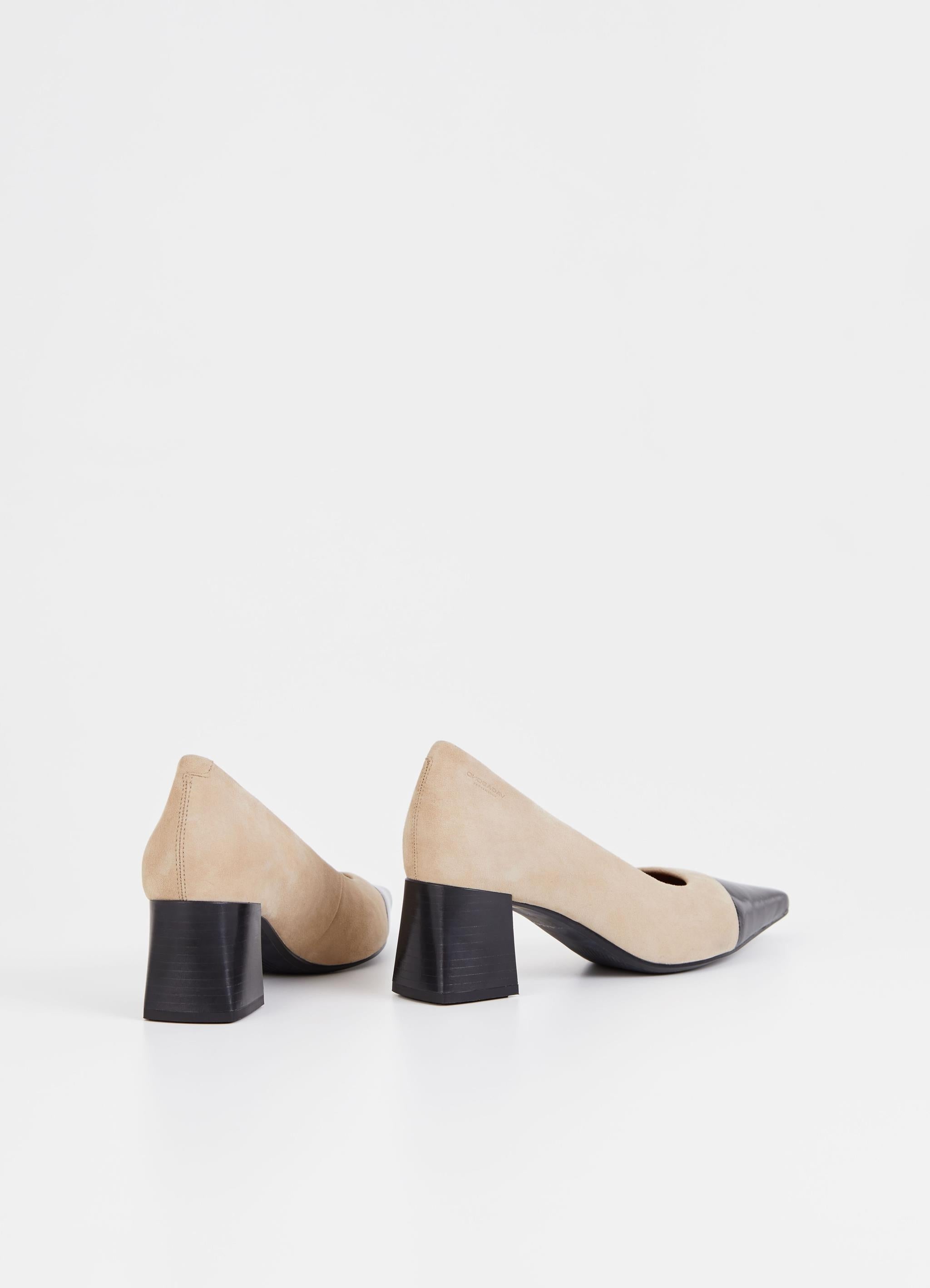 Beige suede pumps with stacked black heel and pointed contrast black patent toe