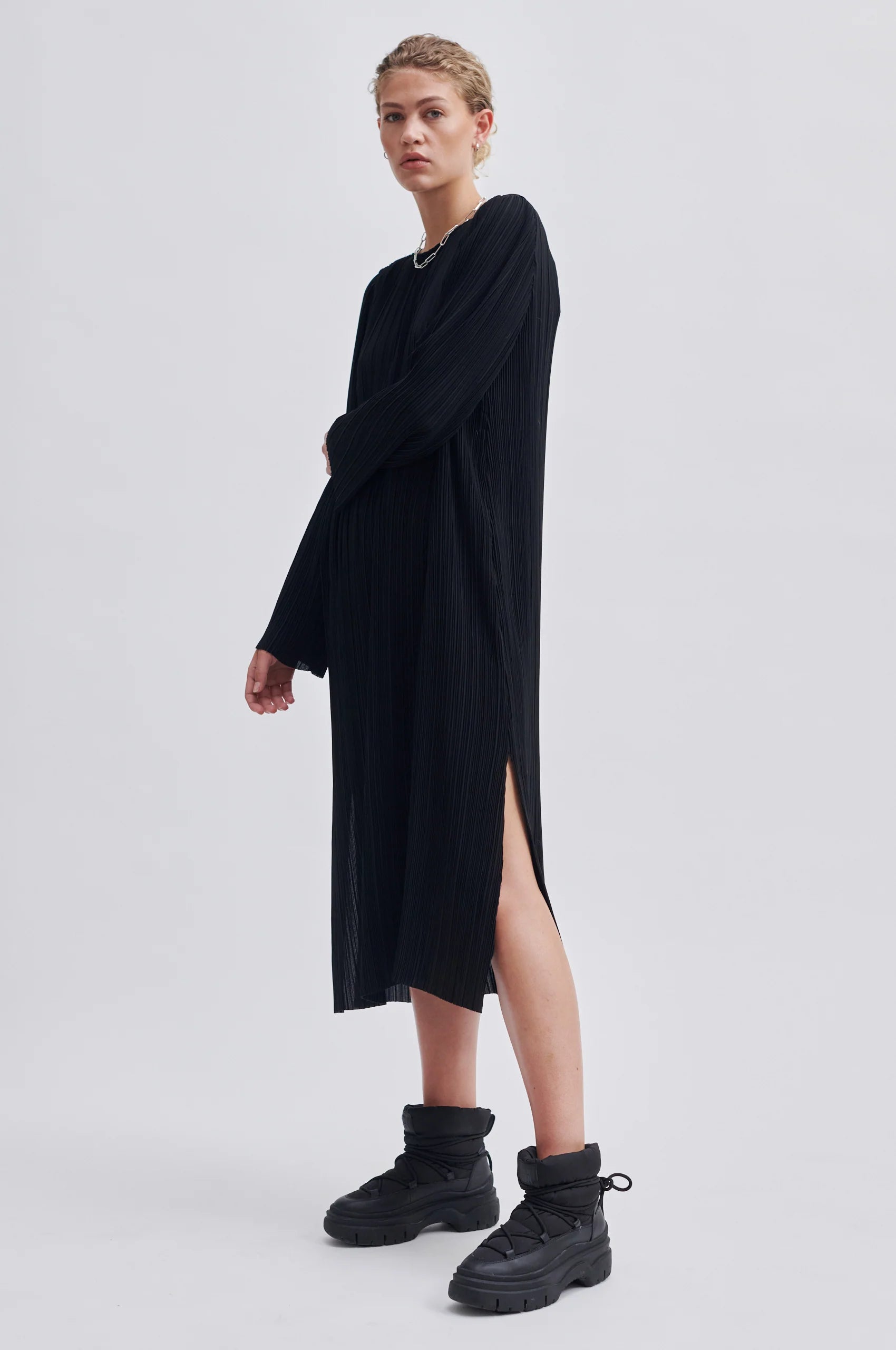 Black micro pleated round neck dress with long sleeves and side splits at the hem