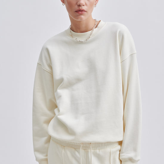 Cream coloured crew neck sweatshirt with ribbed cuffs and hem