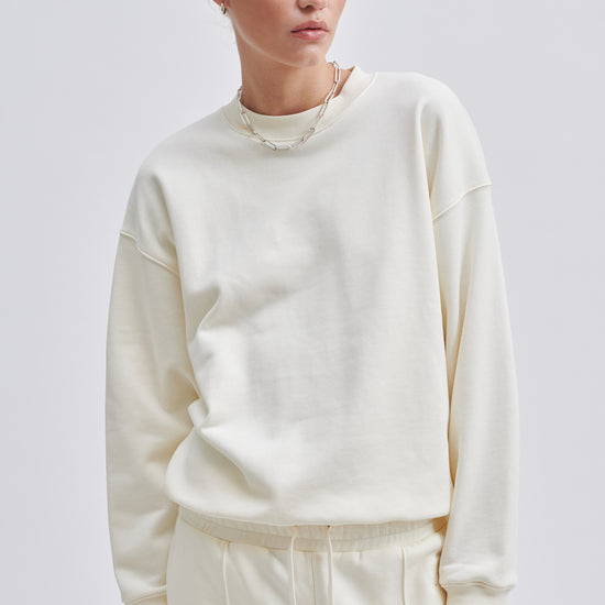 Cream coloured crew neck sweatshirt with ribbed cuffs and hem