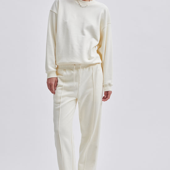 Straight leg cream joggers with side seam pockets and elasticated waistband with drawstring tie