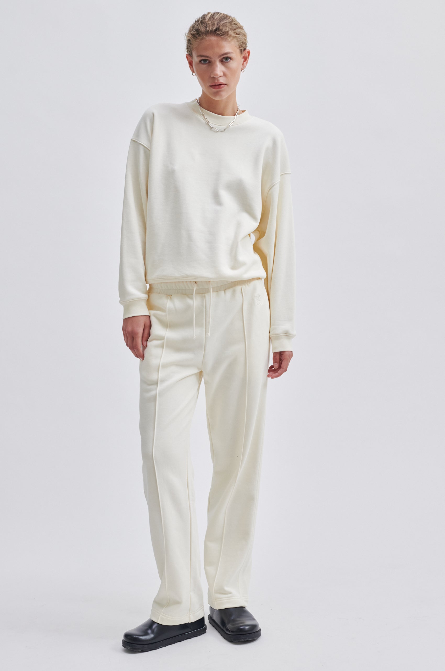 Straight leg cream joggers with side seam pockets and elasticated waistband with drawstring tie