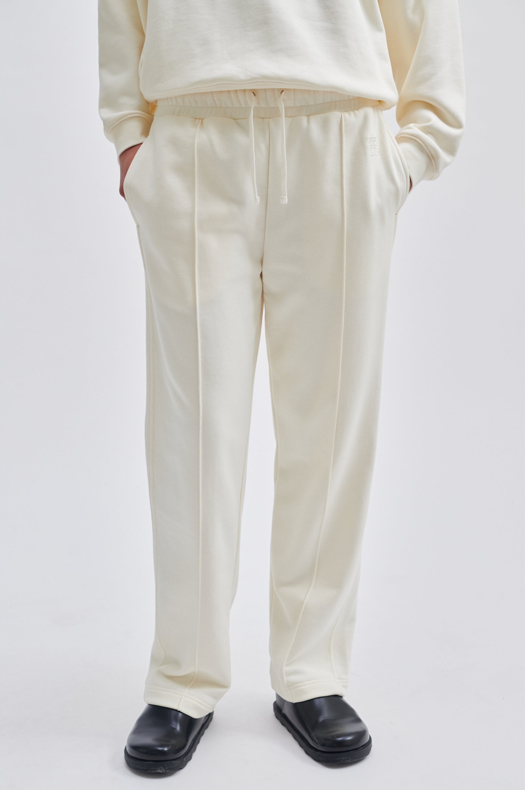 Straight leg cream joggers with side seam pockets and elasticated waistband with drawstring tie